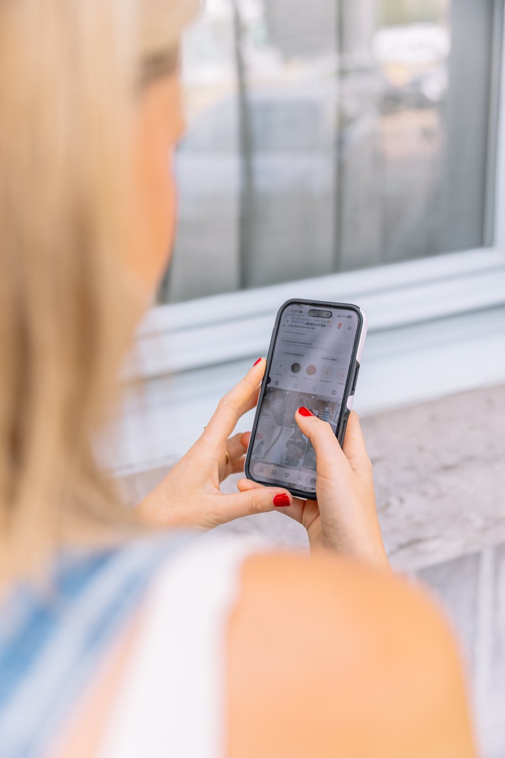 Over de schouder van Sarah die een Instagram-profiel bekijkt op haar telefoon