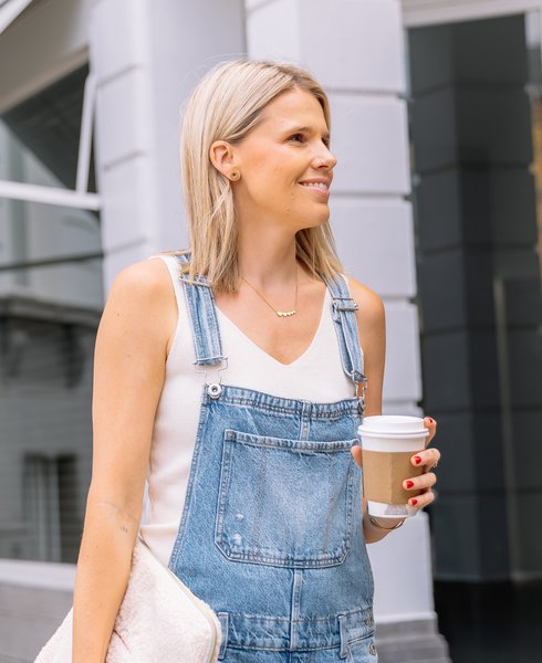 Sarah steekt de straat over met een koffie in de hand